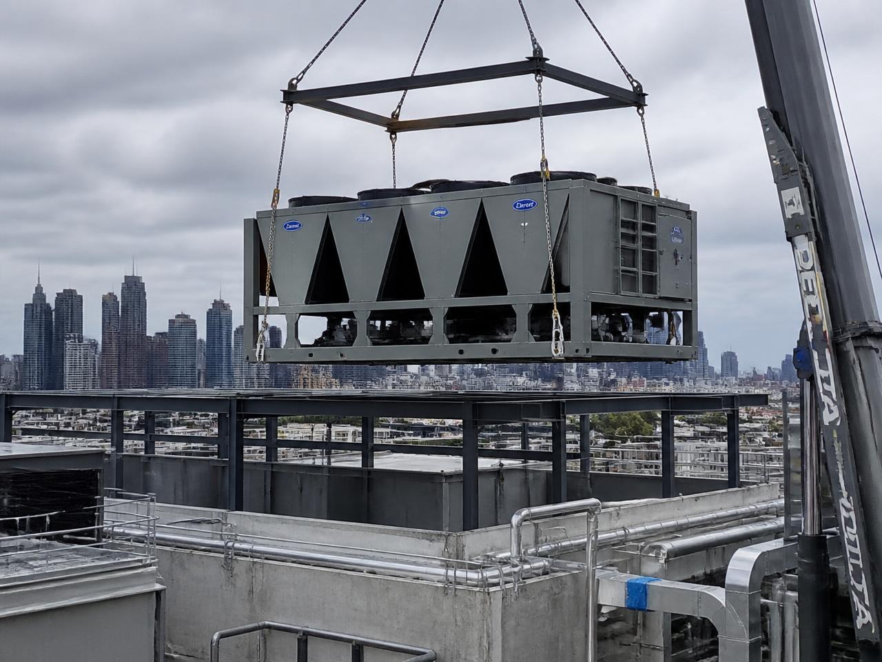 Packaged chiller unit being craned onto a commercial rooftop plant deck