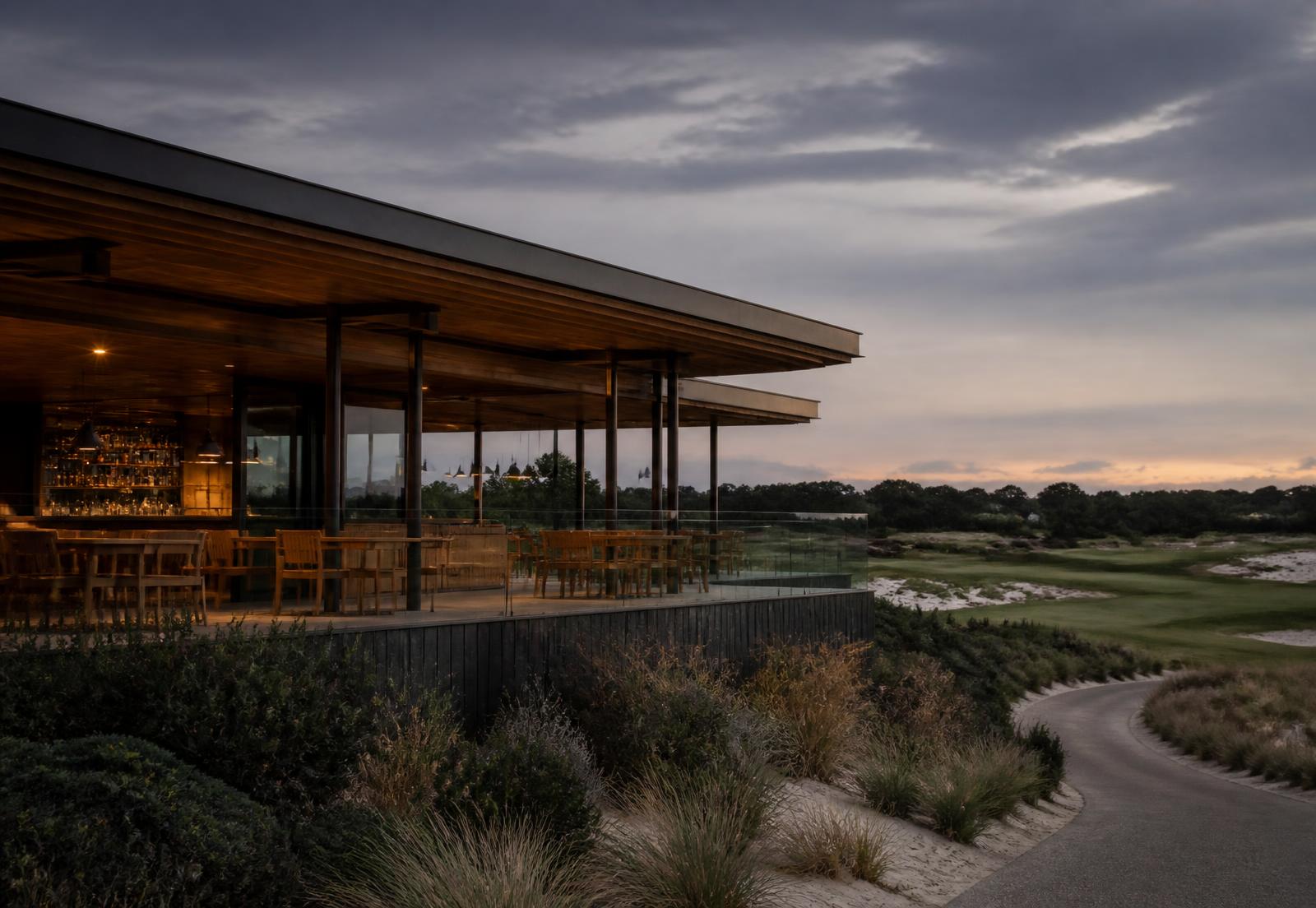 Contemporary golf clubhouse pavilion overlooking sand-belt fairways at dusk